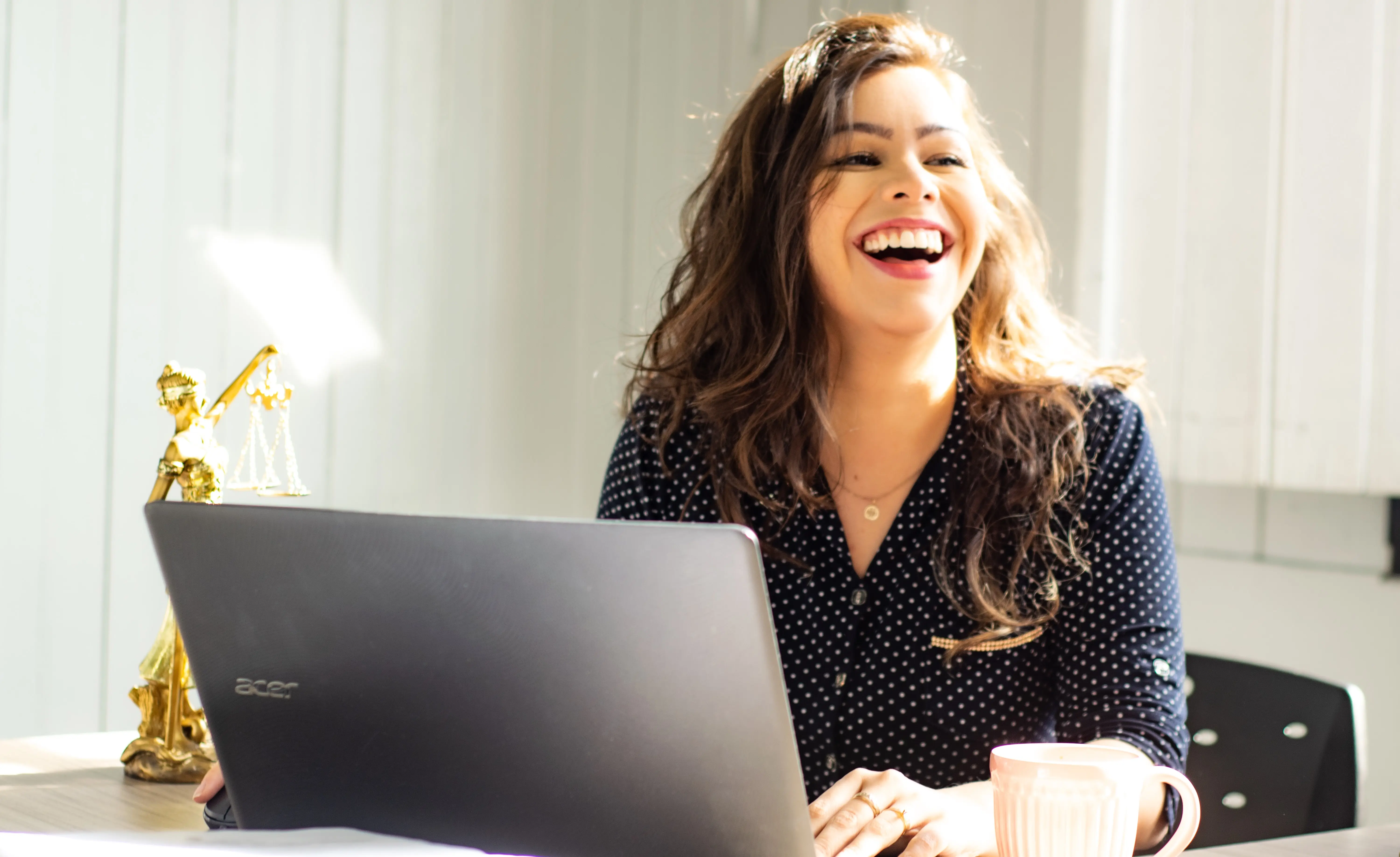 Femme au bureau, sur l'ordinateur avec un grand sourire très agréable.